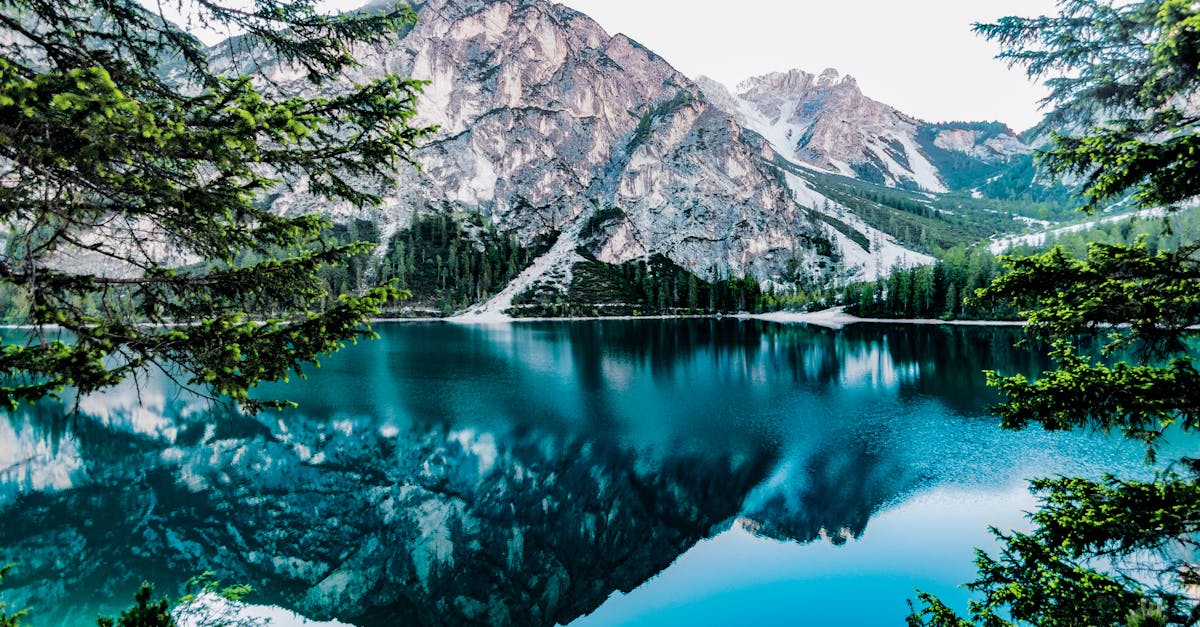 Serene mountain lake with stunning reflections in Braies, Italy, surrounded by trees.